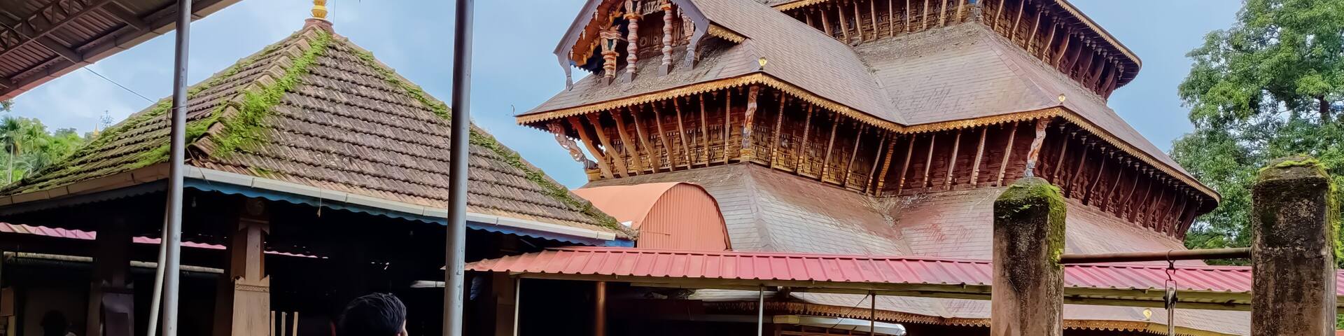 A man standing in front of the ancient Hindu temple rich in architecture design and wood carvings located in Adoor Kerala