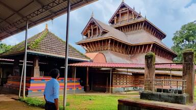 A man standing in front of the ancient Hindu temple rich in architecture design and wood carvings located in Adoor Kerala