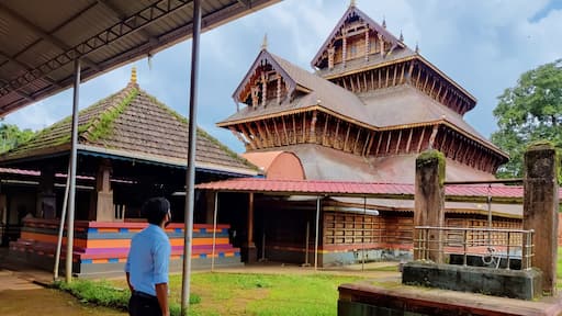 A man standing in front of the ancient Hindu temple rich in architecture design and wood carvings located in Adoor Kerala