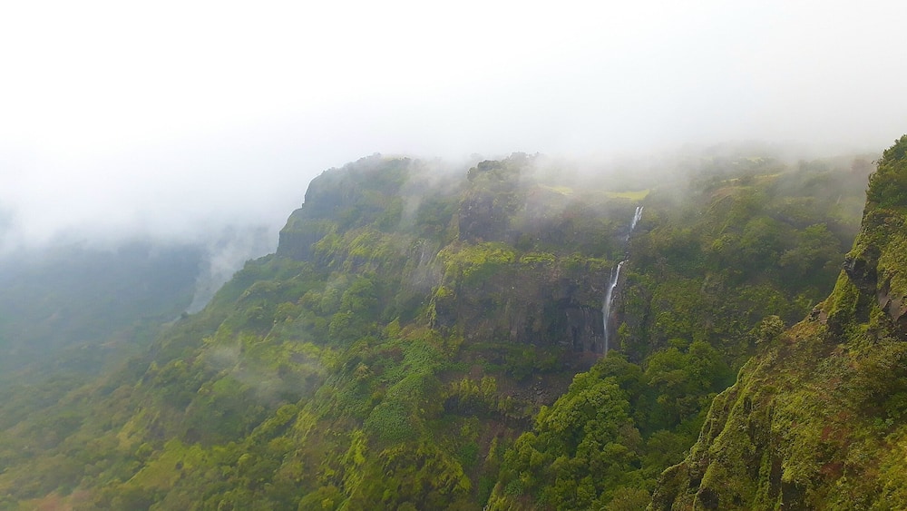 A lush green mountain with a waterfall cascading down its side.
