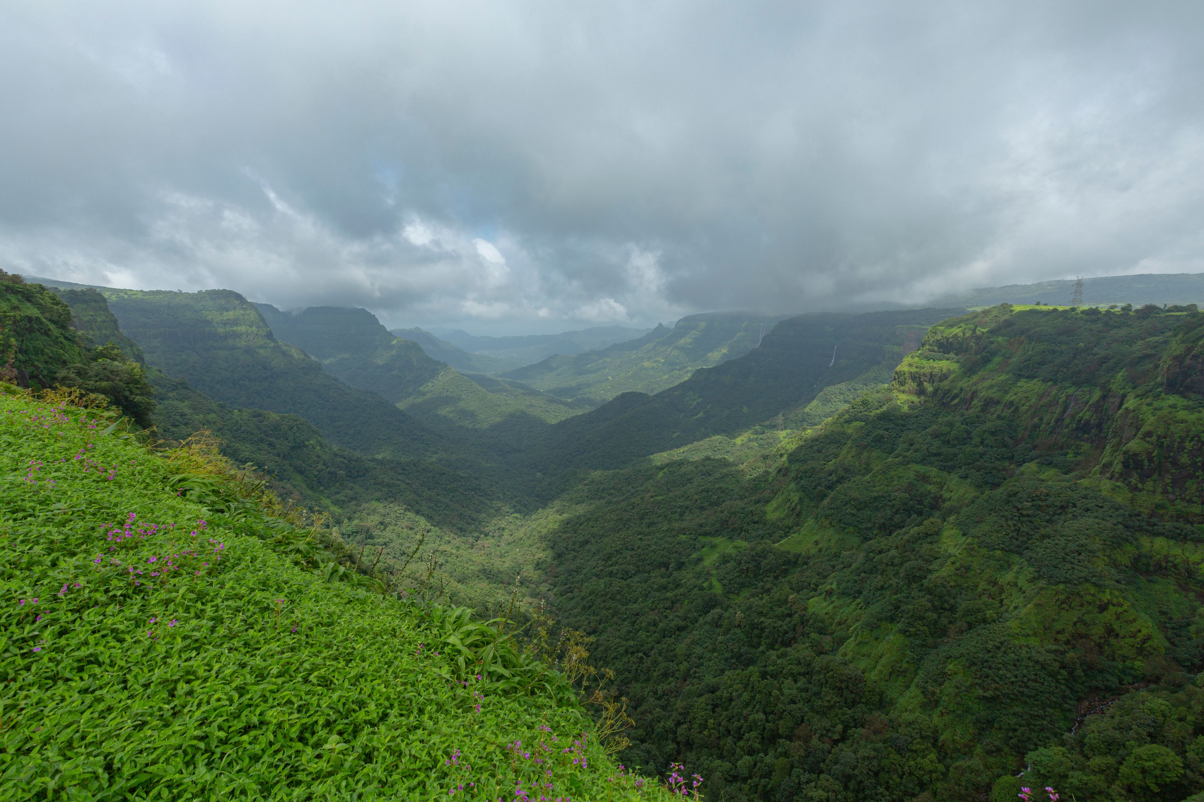 A lush green valley with steep hills and a cloudy sky.