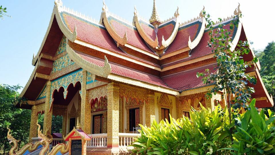 A multi-tiered temple with ornate golden decorations and a red roof.