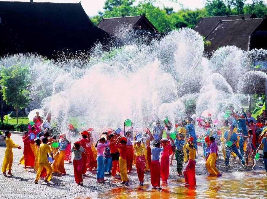 A group of people in colorful costumes dancing in a water fountain.