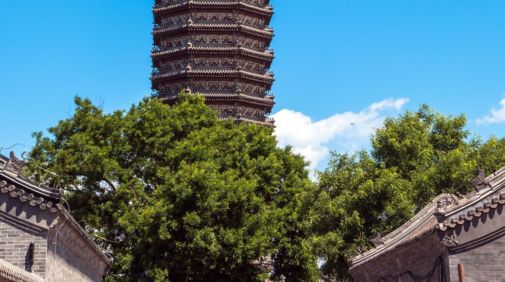 A traditional multi-tiered pagoda with intricate roof designs, set against a clear blue sky.