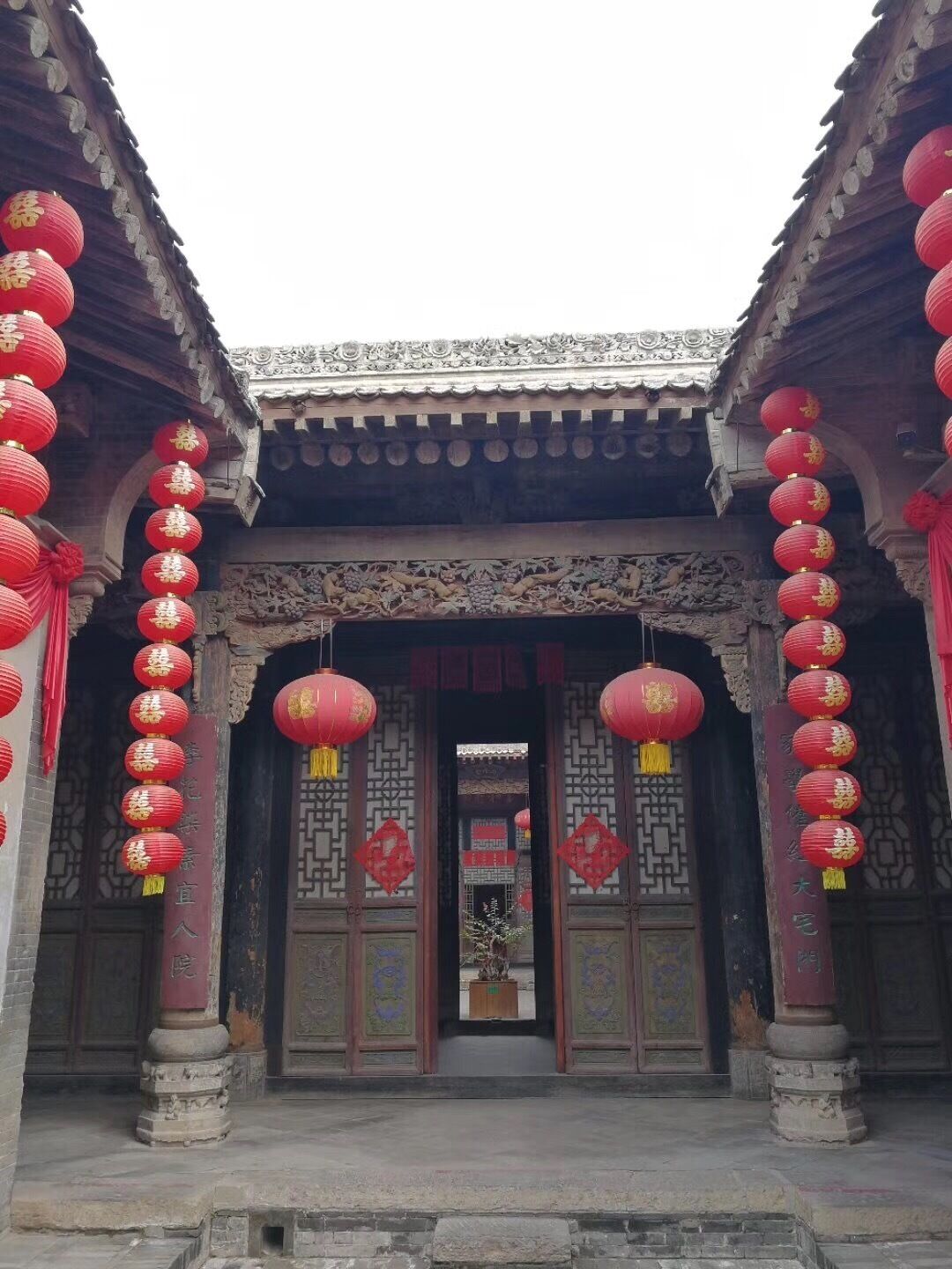 A traditional Chinese building entrance with red lanterns and intricate carvings.