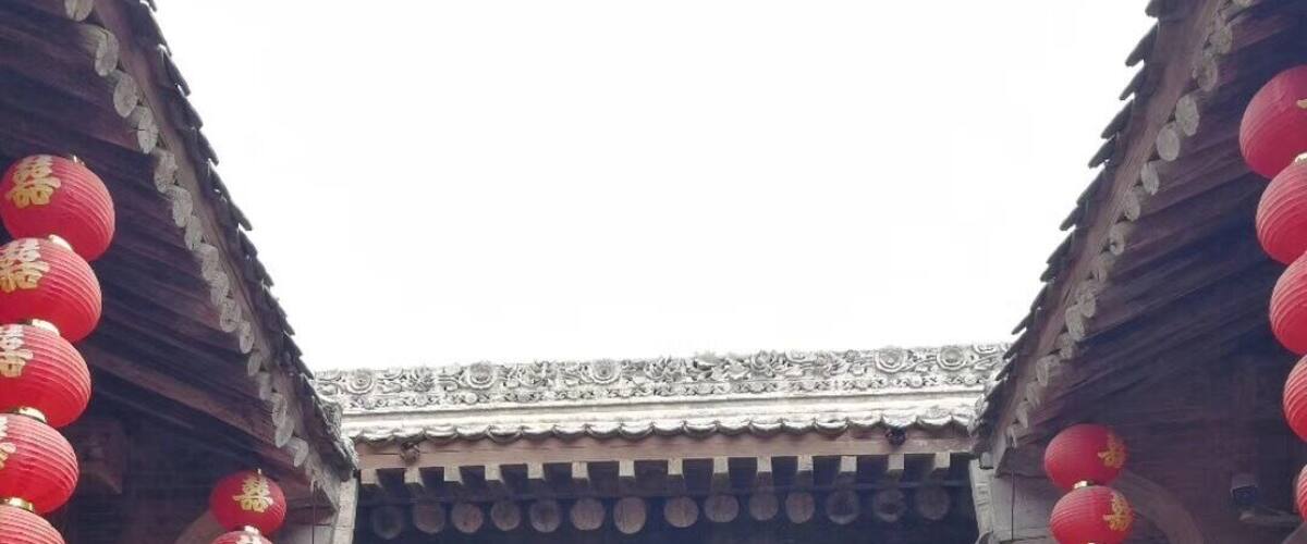 A traditional Chinese building entrance with red lanterns and intricate carvings.