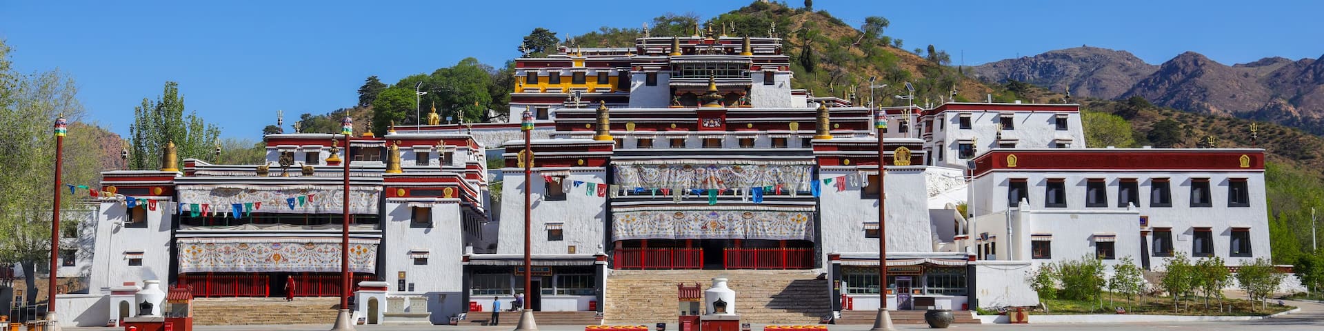 A multi-tiered temple complex with intricate architecture, set against a backdrop of mountains and clear skies.