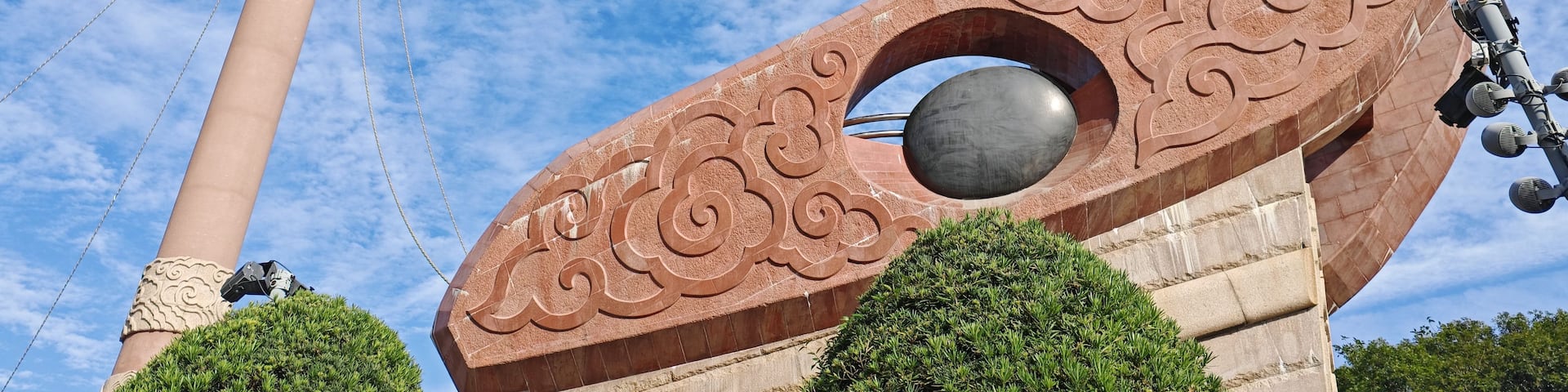 A tall monument with a spiral design, a tall tower, and a circular structure with a reflective surface.