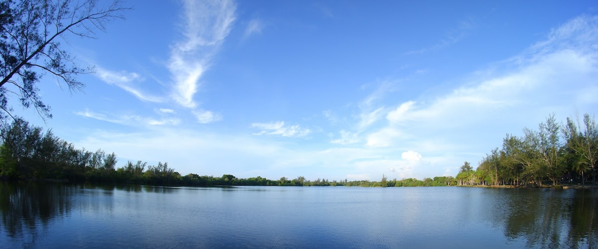 A calm lake with clear blue sky and sparse clouds.