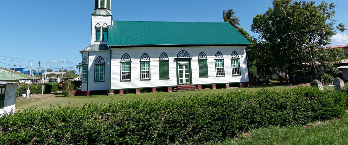 A white church with a green roof and a tall steeple.