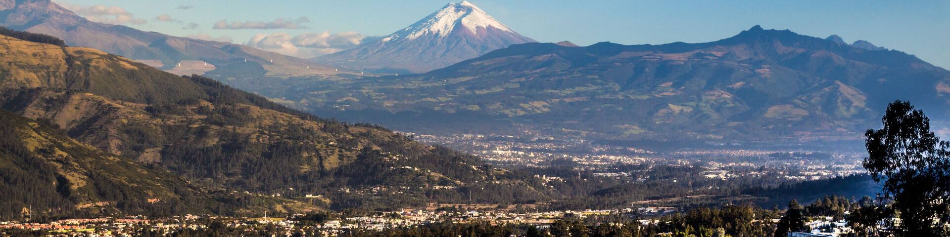 A mountain range with a prominent peak, a valley with a town, and a clear sky.