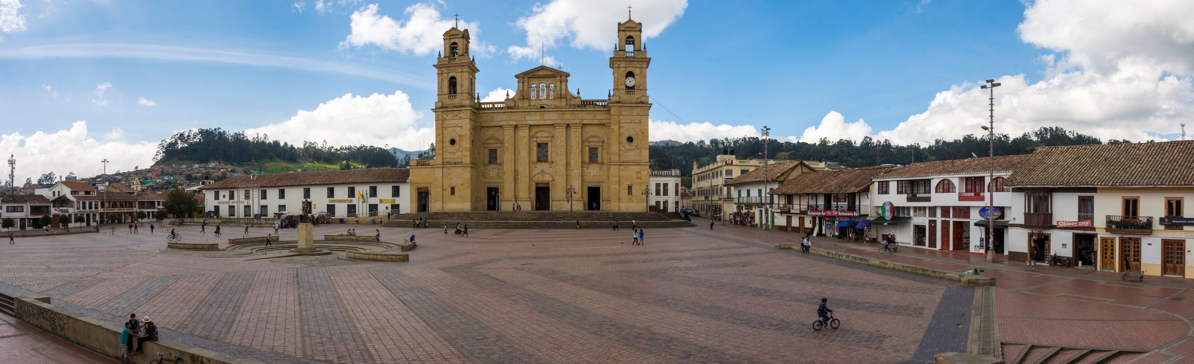 A historic church with two towers, a plaza with people, and surrounding buildings.