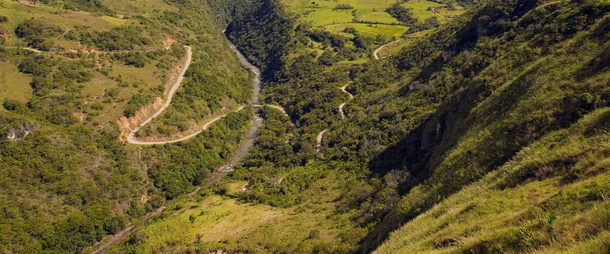 A valley with winding roads and lush green hills.