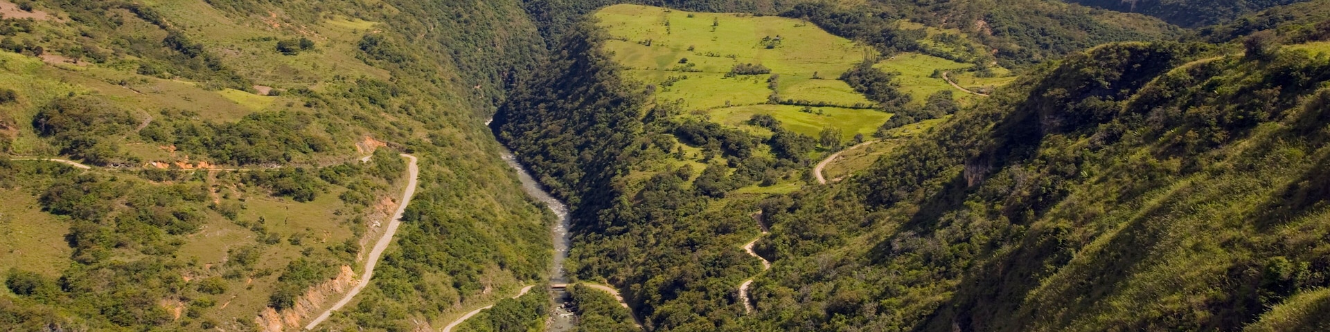 A valley with winding roads and lush green hills.