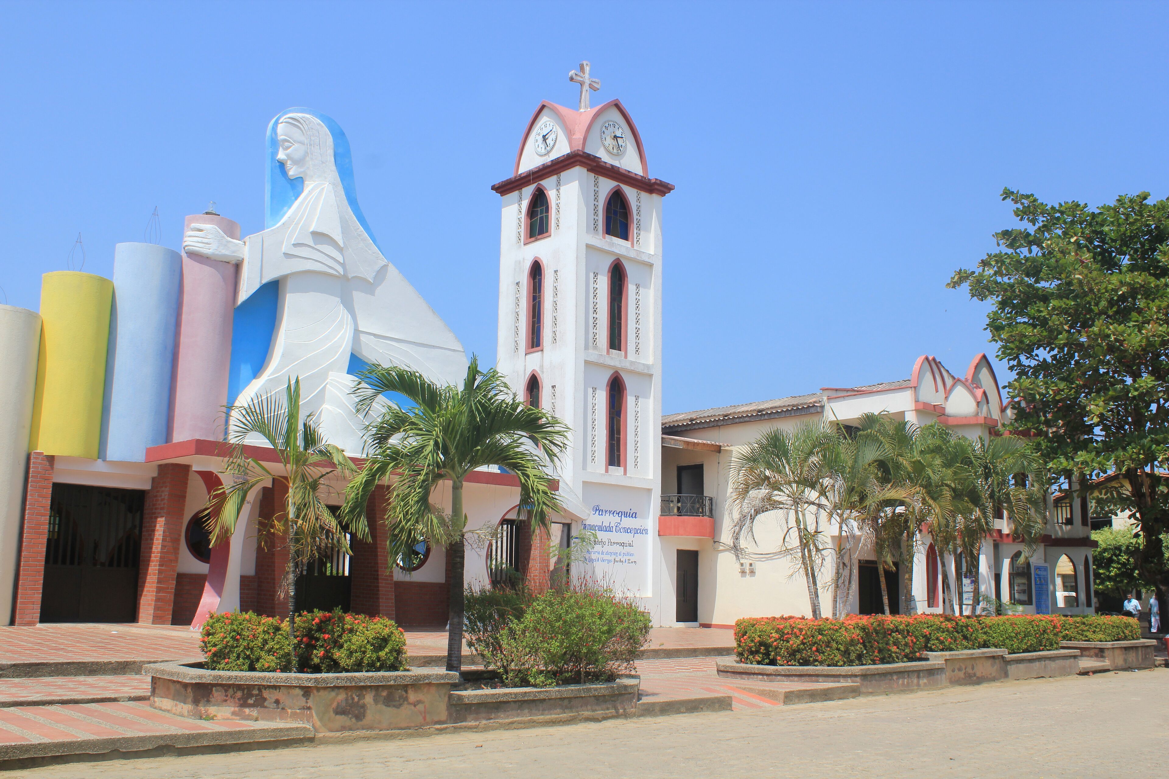 A church with a bell tower and a large statue of a woman.