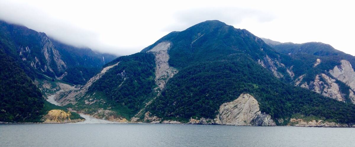 A mountainous landscape with a body of water in the foreground.