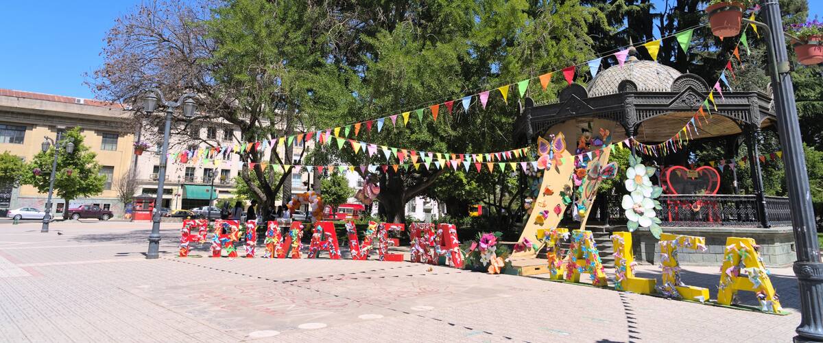 A festive outdoor event with colorful decorations, a stage, and a clear blue sky.