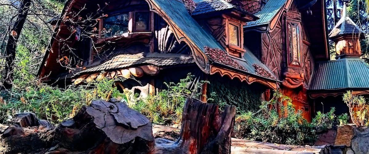 A wooden house built on a tree stump with a steep roof and a tower.