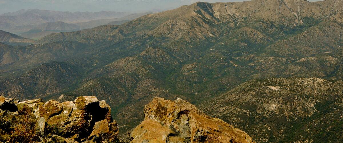 A mountainous landscape with rugged terrain and distant snow-capped peaks.
