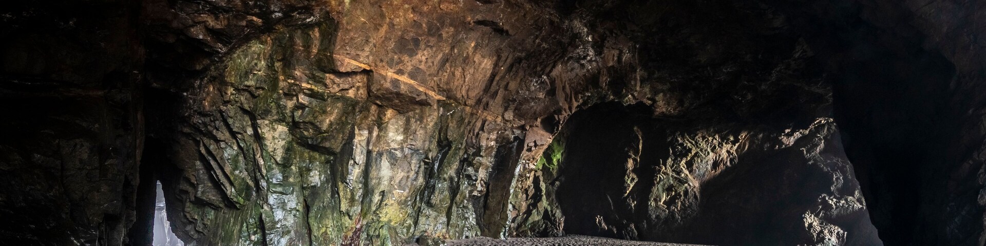 Una cueva con paredes rocosas y suelo arenoso.