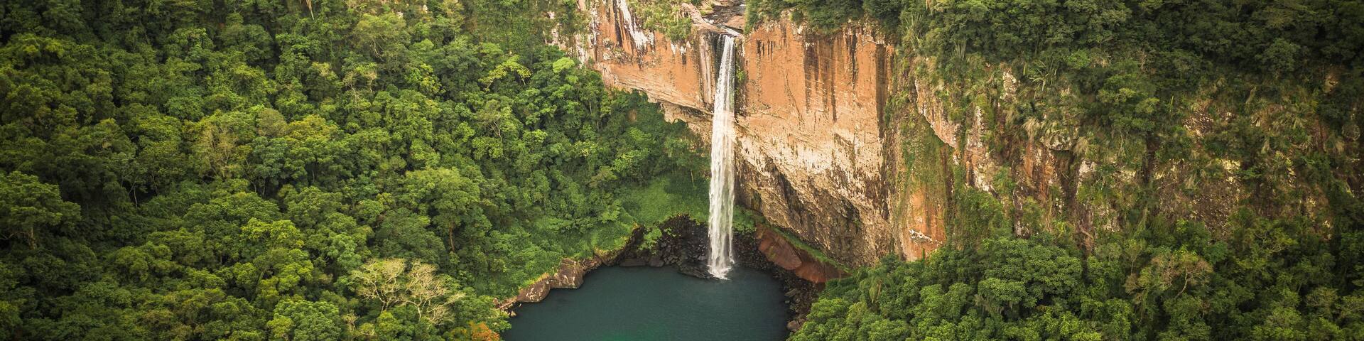Aerial View Of Tall Waterfall And Lake Surrounded By Lush Green Forest In Rolante, Rio Grande Do Sul, Brazil.