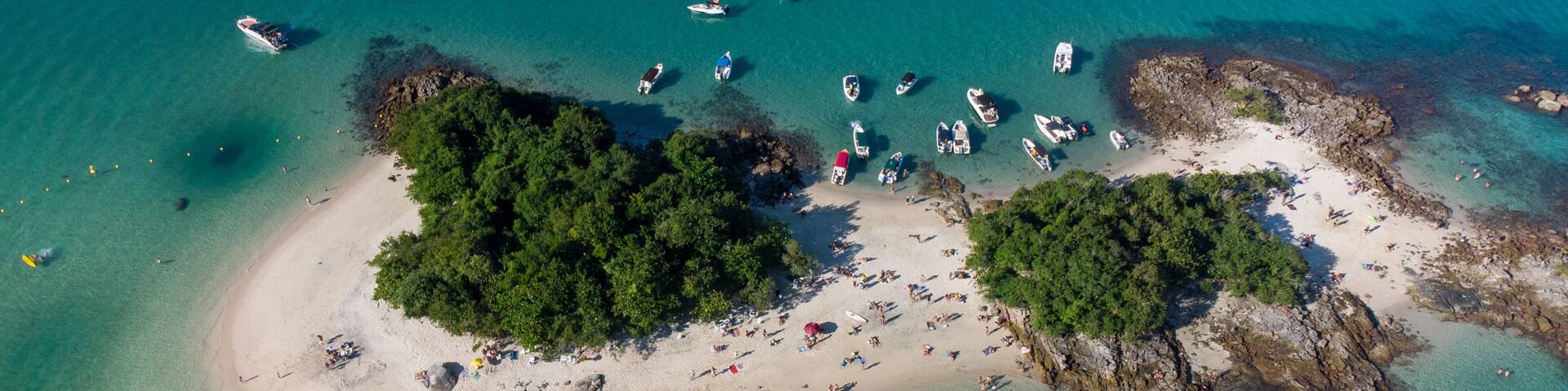 An aerial view of a tropical island with clear turquoise waters, sandy beaches, and lush green vegetation.