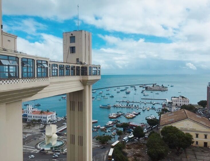 A coastal cityscape with a prominent bridge, marina, and historic buildings.