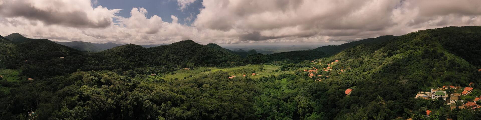 A lush green valley with scattered houses and mountains in the background.