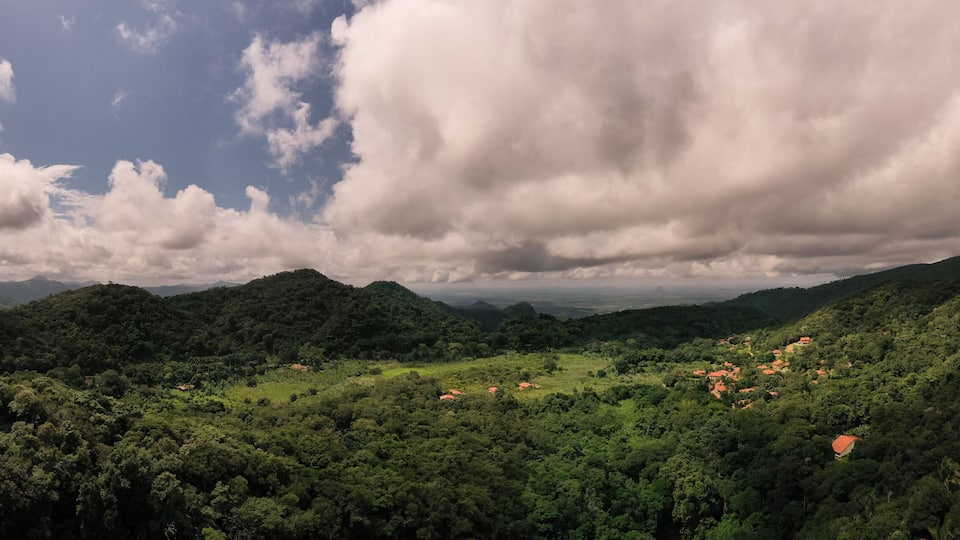 A lush green valley with scattered houses and mountains in the background.