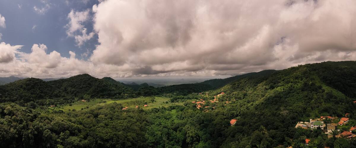 A lush green valley with scattered houses and mountains in the background.