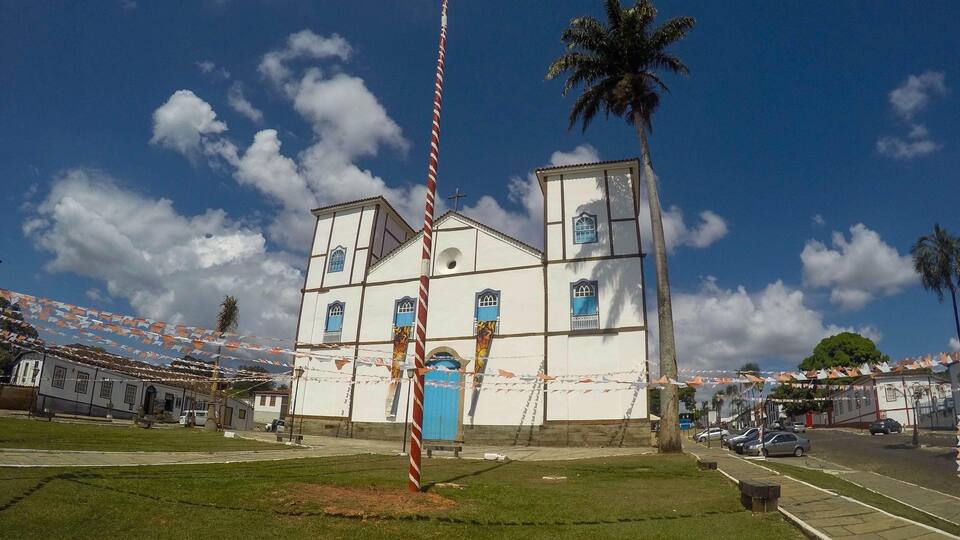 A church with a bell tower, surrounded by palm trees and a clear blue sky.