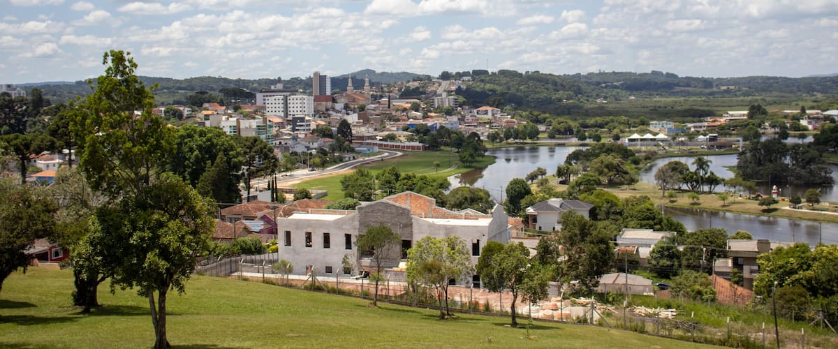 A cityscape with a river, green hills, and a clear sky.