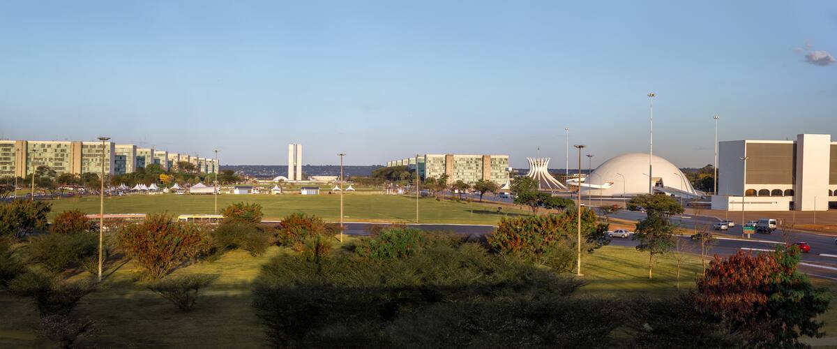A cityscape with modern buildings, a large dome structure, and a park with trees.