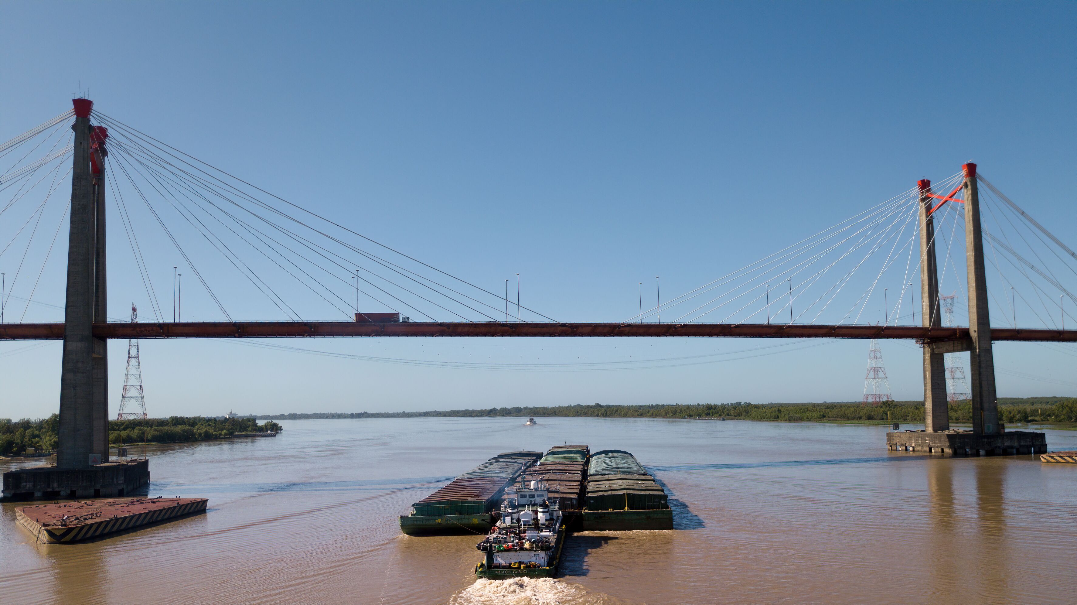 A bridge spanning a river with a cargo ship passing underneath.