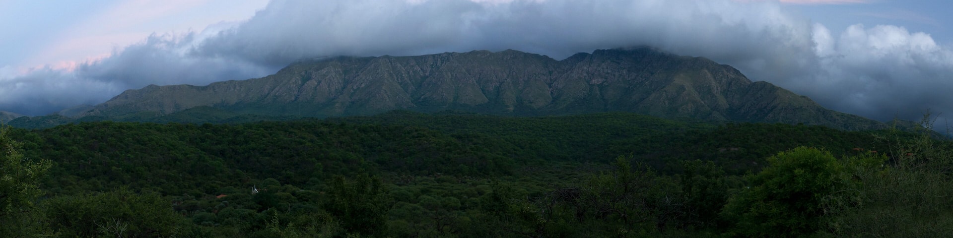 Magical view of popular landmark Uritorco hill, valley and green forest at sunset, in Capilla del Monte, Cordoba, Argentina.