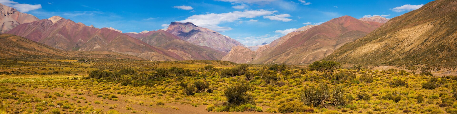 Paisaje montañoso con vegetación verde y cielo azul despejado.
