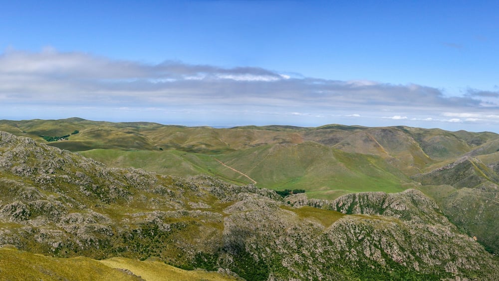 Un paysage montagneux, avec des collines douces et un ciel dégagé.