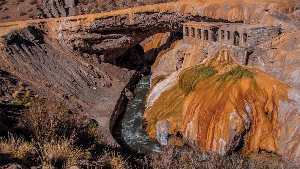 Ein Fluss, der durch eine Schlucht fließt, mit einer Brücke und einer großen Felsformation.