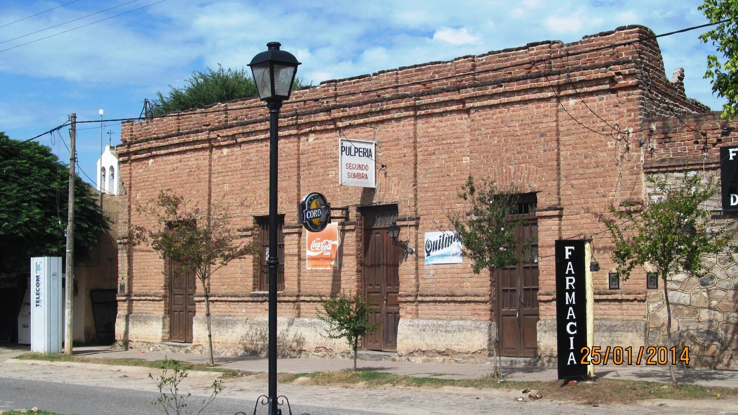 A historic brick building with signs for 'Pulperia Segundo Sombra' and 'Farmacia'.