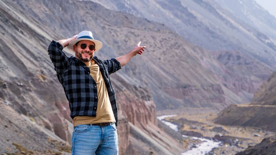 A person standing on a rocky terrain with a mountainous background.