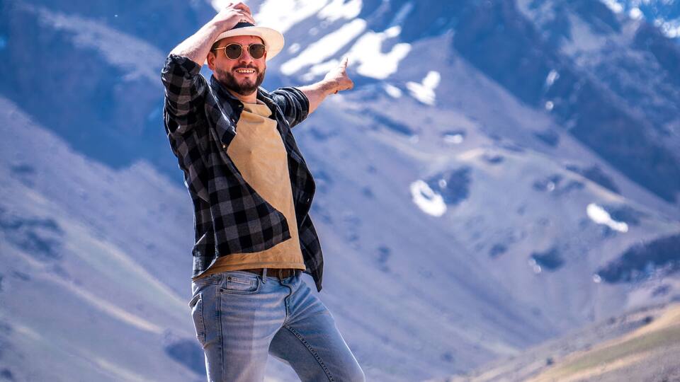 A person standing on a rock with a mountainous landscape in the background.