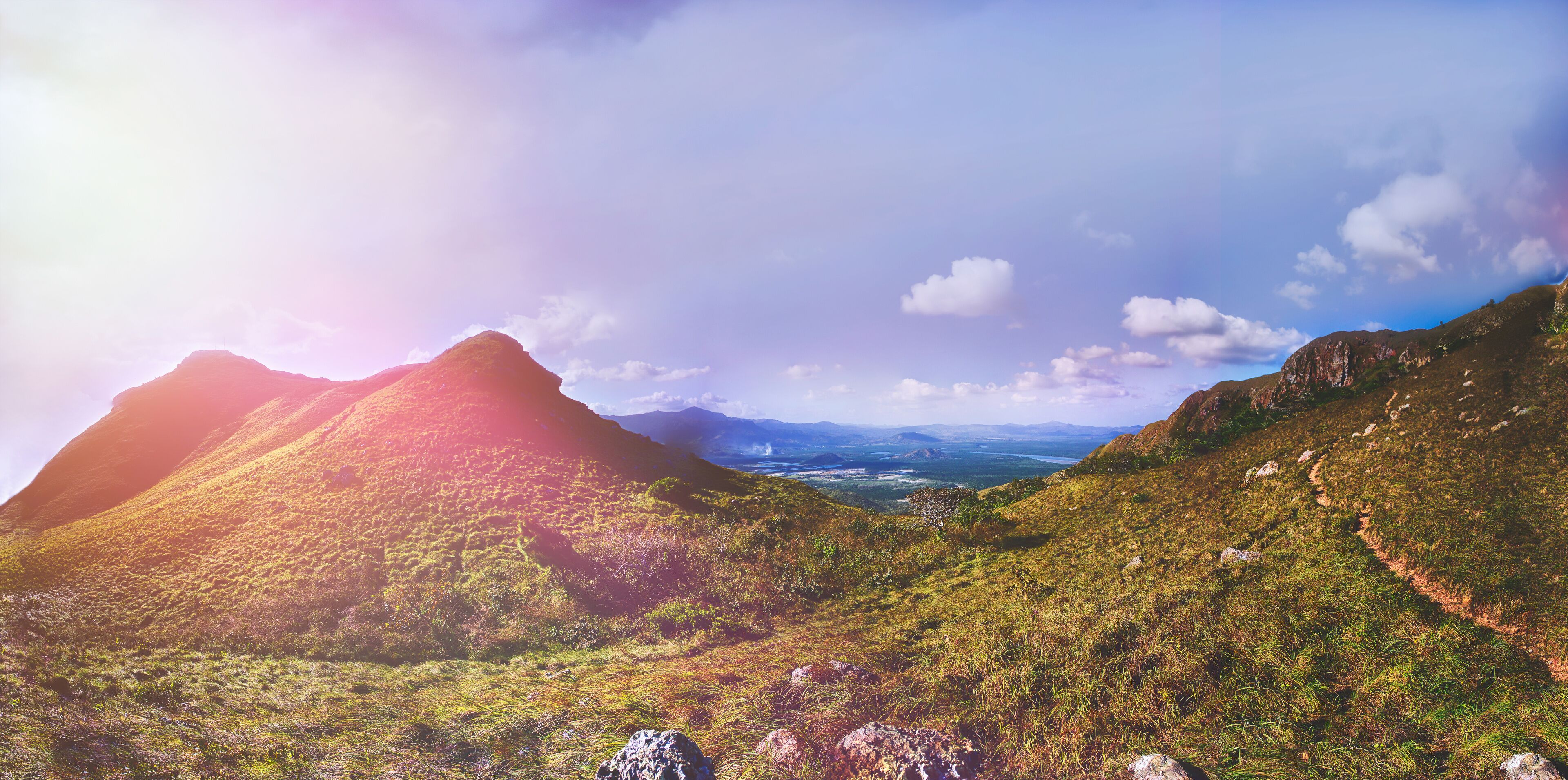 A mountainous landscape with a valley and distant mountains.