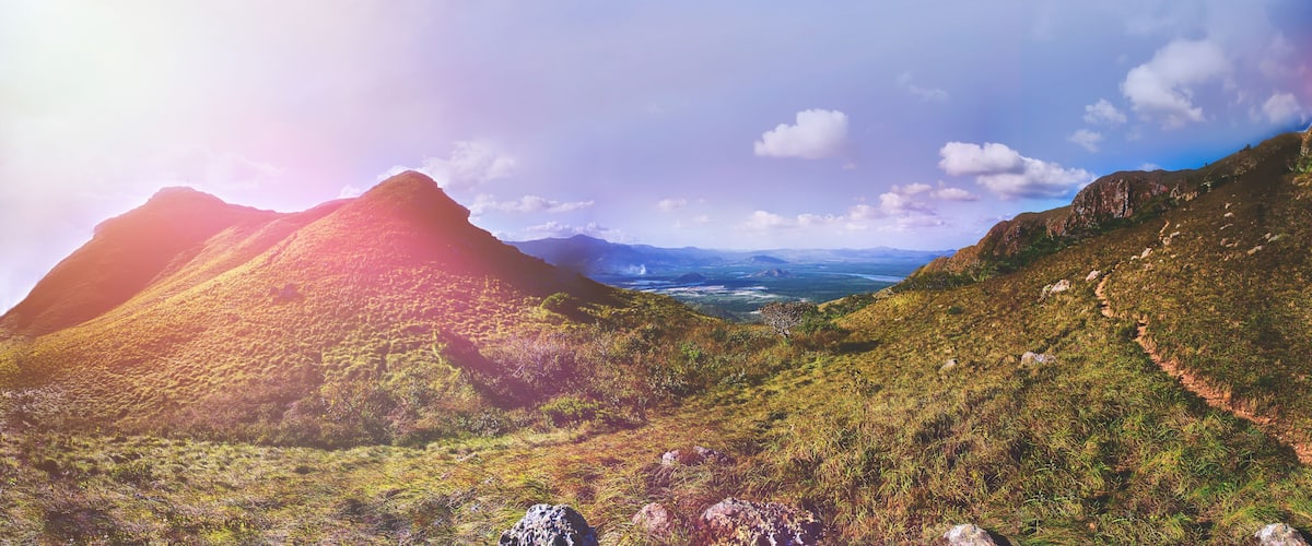 A mountainous landscape with a valley and distant mountains.