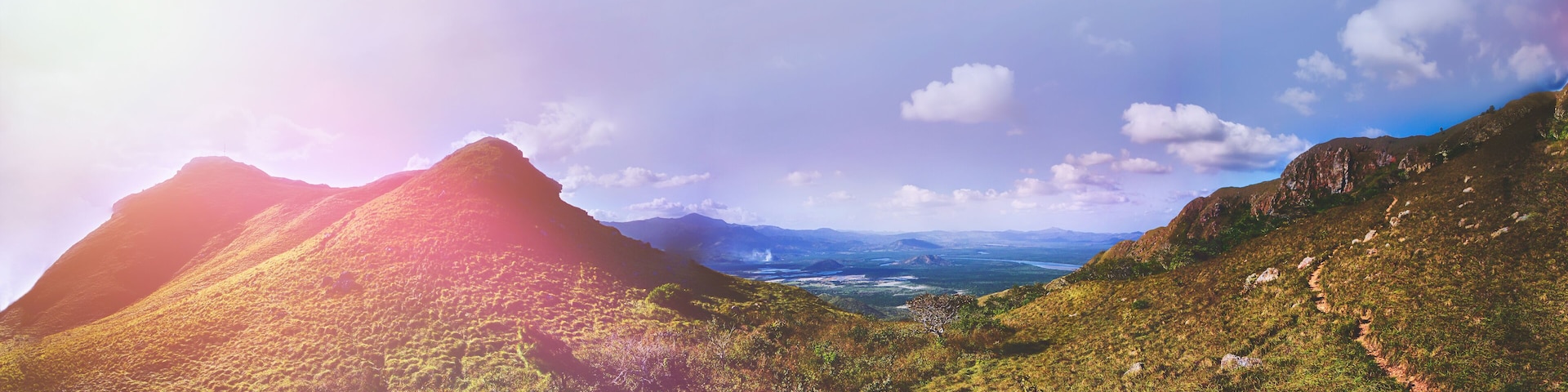 A mountainous landscape with a valley and distant mountains.