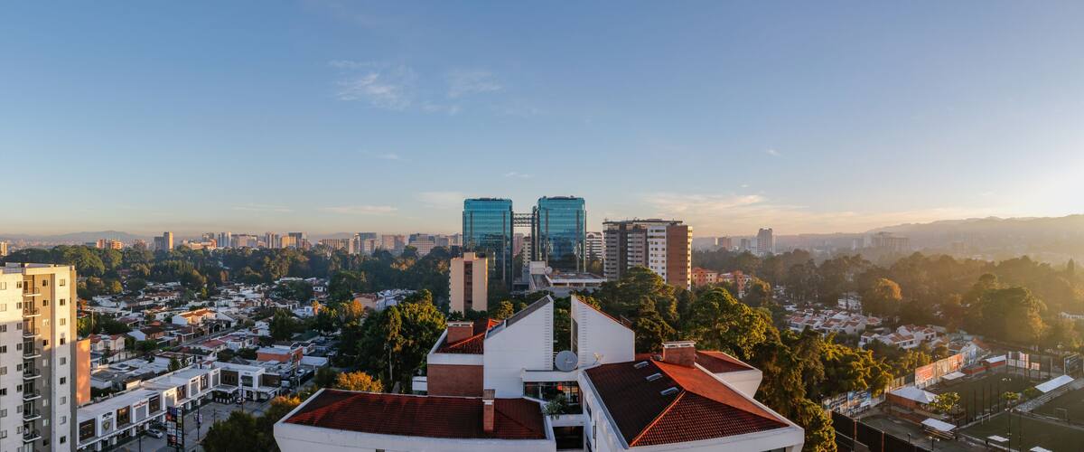 Un paisaje urbano con edificios modernos, una combinación de zonas residenciales y comerciales, y un cielo despejado.