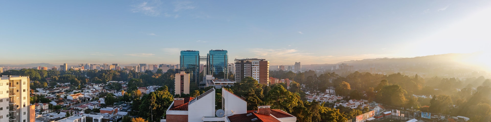 Un paisaje urbano con edificios modernos, una combinación de zonas residenciales y comerciales, y un cielo despejado.
