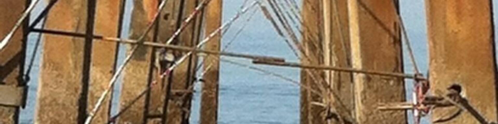 Un muelle con soportes de madera y cables de metal que se adentra en el agua.