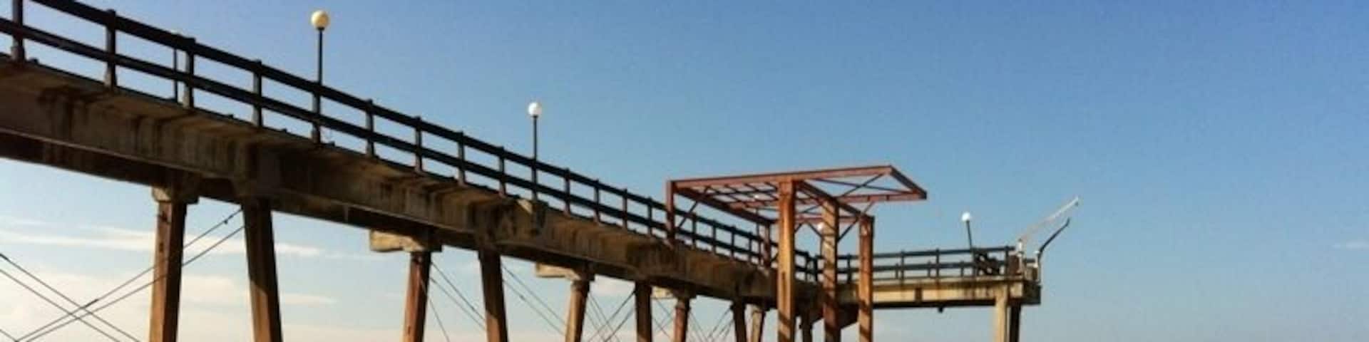 A pier extending into the water with a wooden walkway and a shelter.