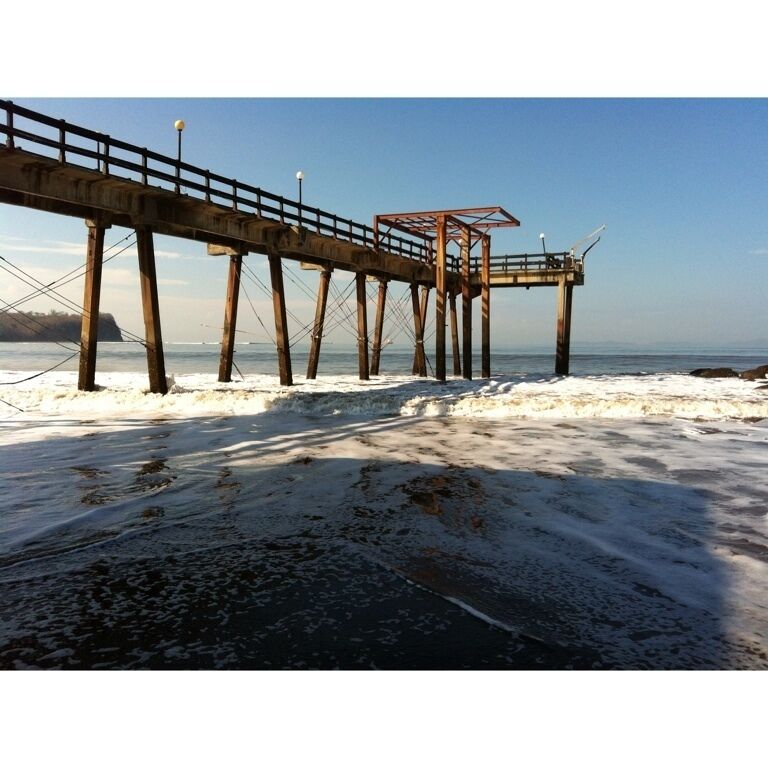 A pier extending into the water with a wooden walkway and a shelter.