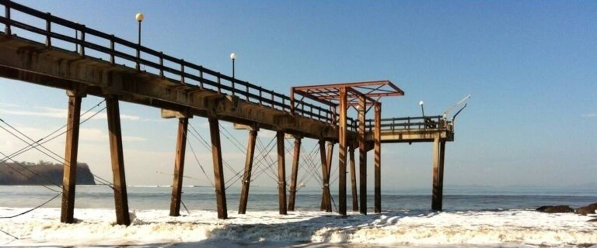 A pier extending into the water with a wooden walkway and a shelter.
